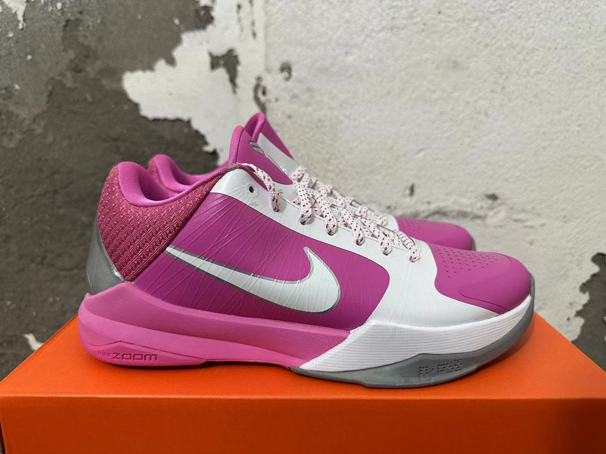 Side view of a pink and white Nike basketball shoe with a silver Swoosh and pink midsole.