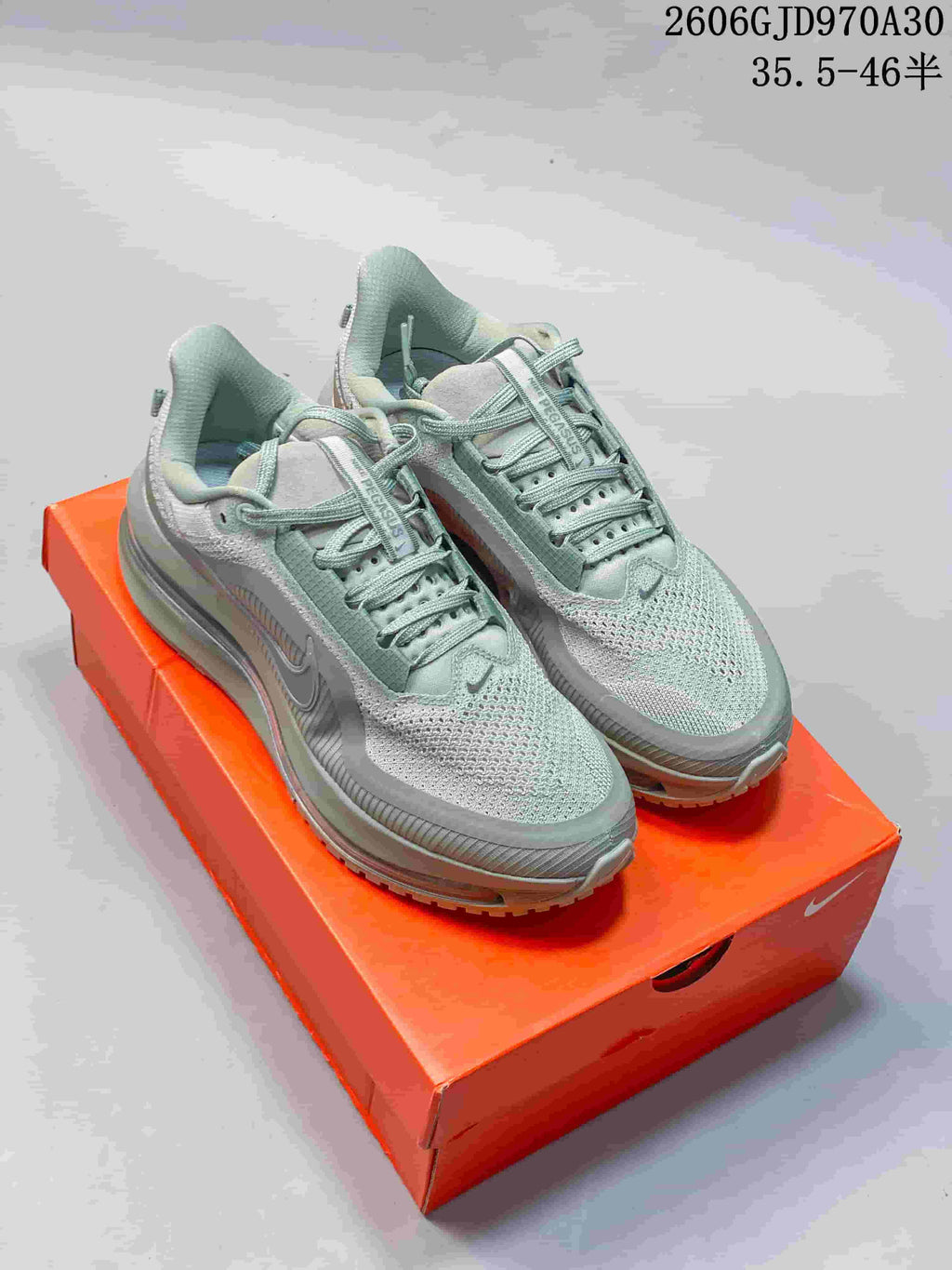 Pair of sage-green Nike Pegasus Premium shoes displayed on an orange box
