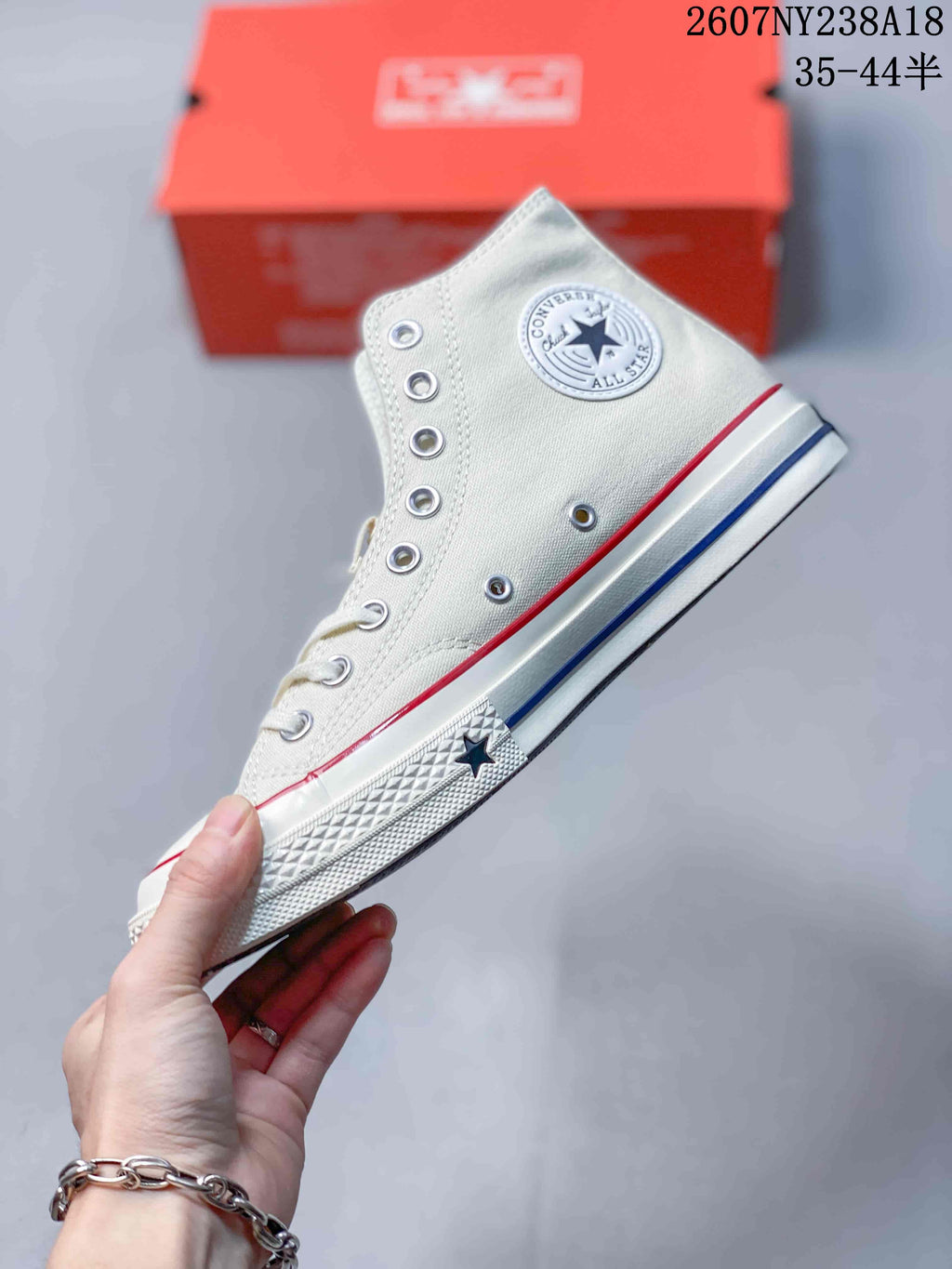 Side profile of an off-white Converse high-top sneaker showing the ankle patch, metal eyelets, rubber toe cap, and star sidewall detail.