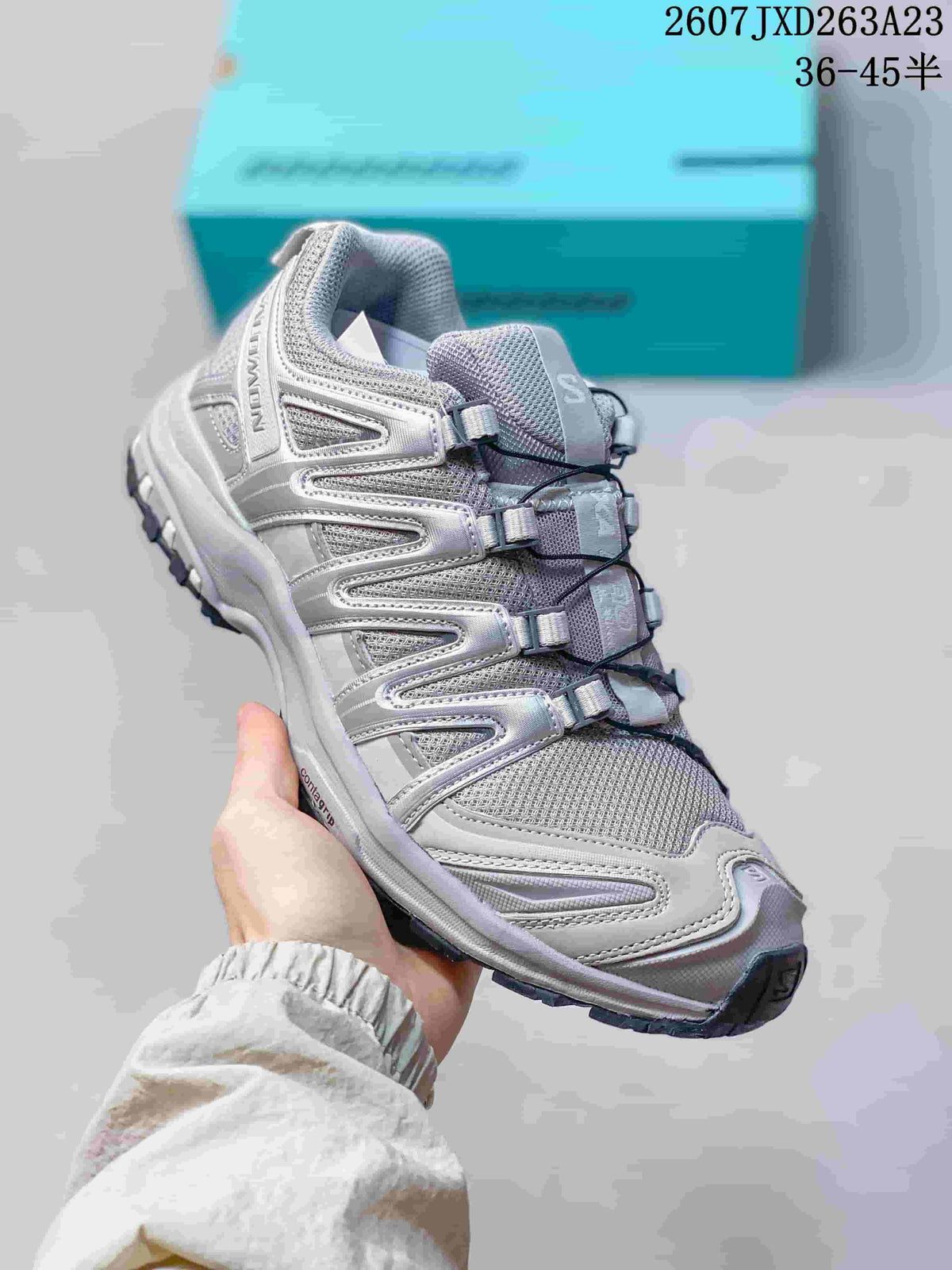 Angled side view of the Salomon XA Pro 3D sneaker showing the gray and silver upper, cord fastening system, padded collar, and dark outsole.