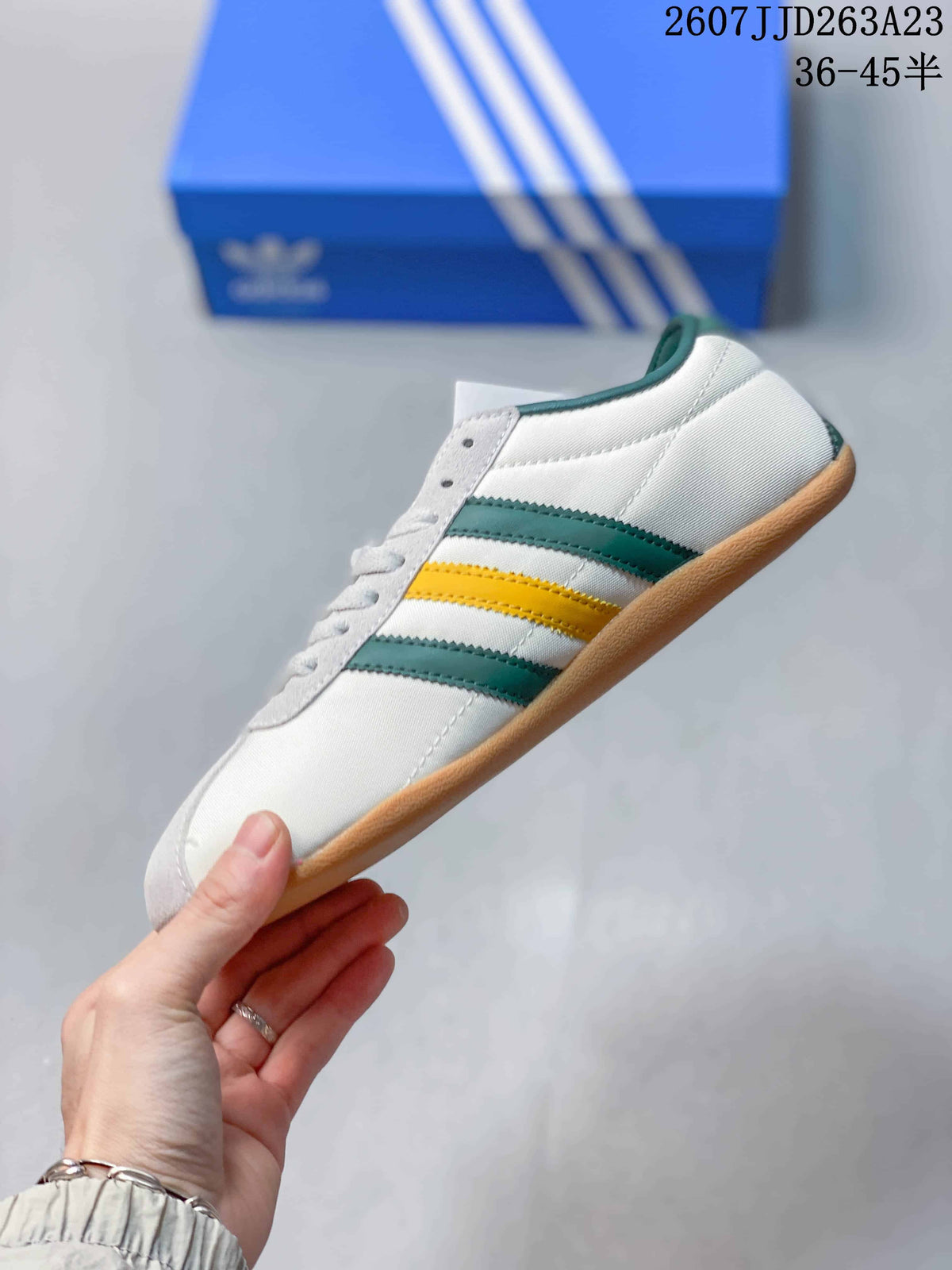 Side profile showing the white low-top sneaker, green and yellow stripes, green collar and gum outsole.