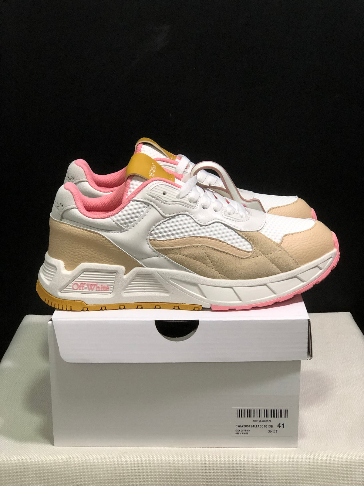 Side view of the white and beige sneakers with pink lining, pink outsole accents and gum-colored tread sections.