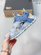 Side profile of the sandal showing adjustable straps, open side panels, and a raised treaded sole.
