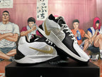 Angled view of a pair of white and black Nike basketball shoes with gold-tone Swooshes