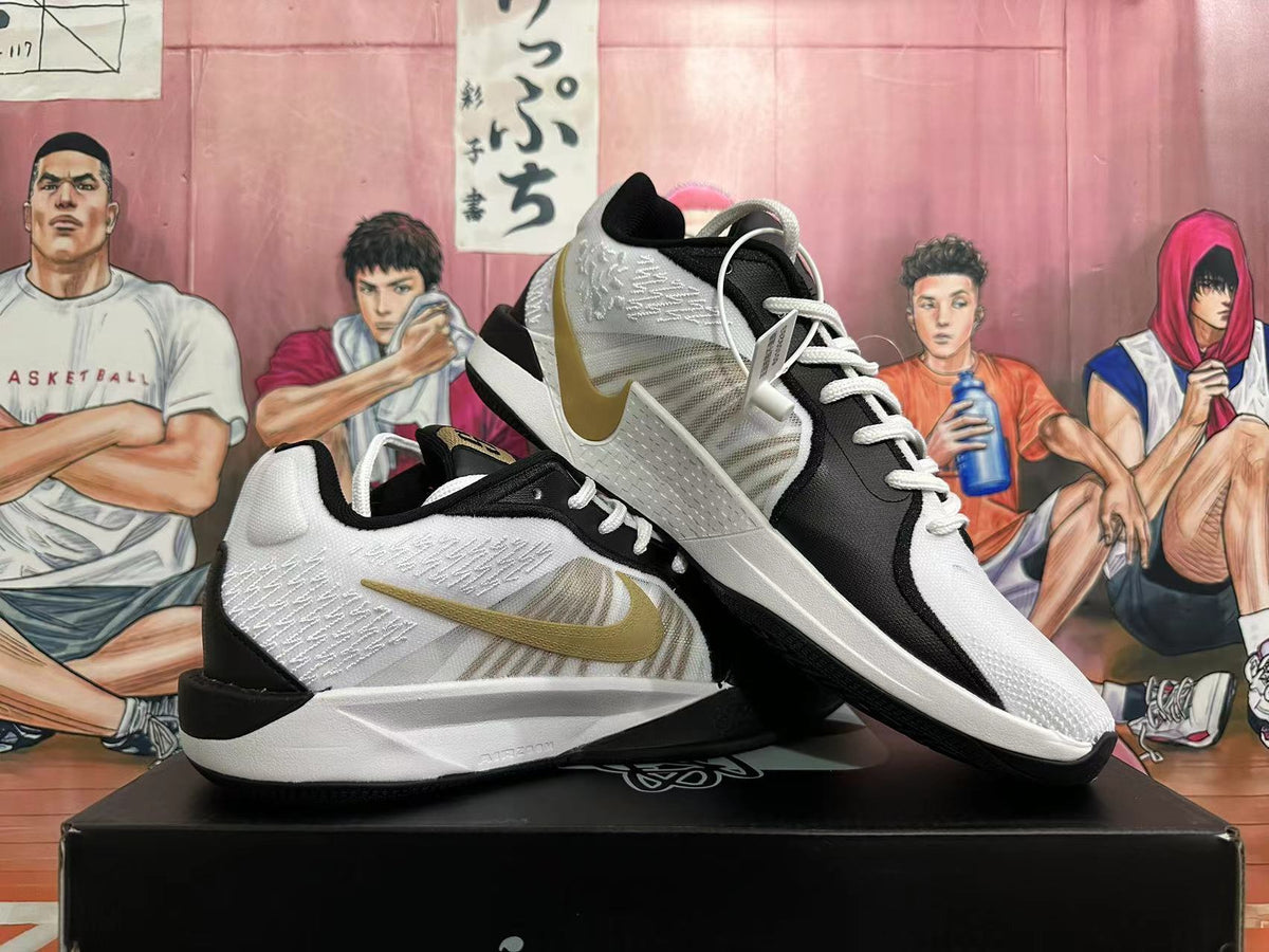 Angled view of a pair of white and black Nike basketball shoes with gold-tone Swooshes