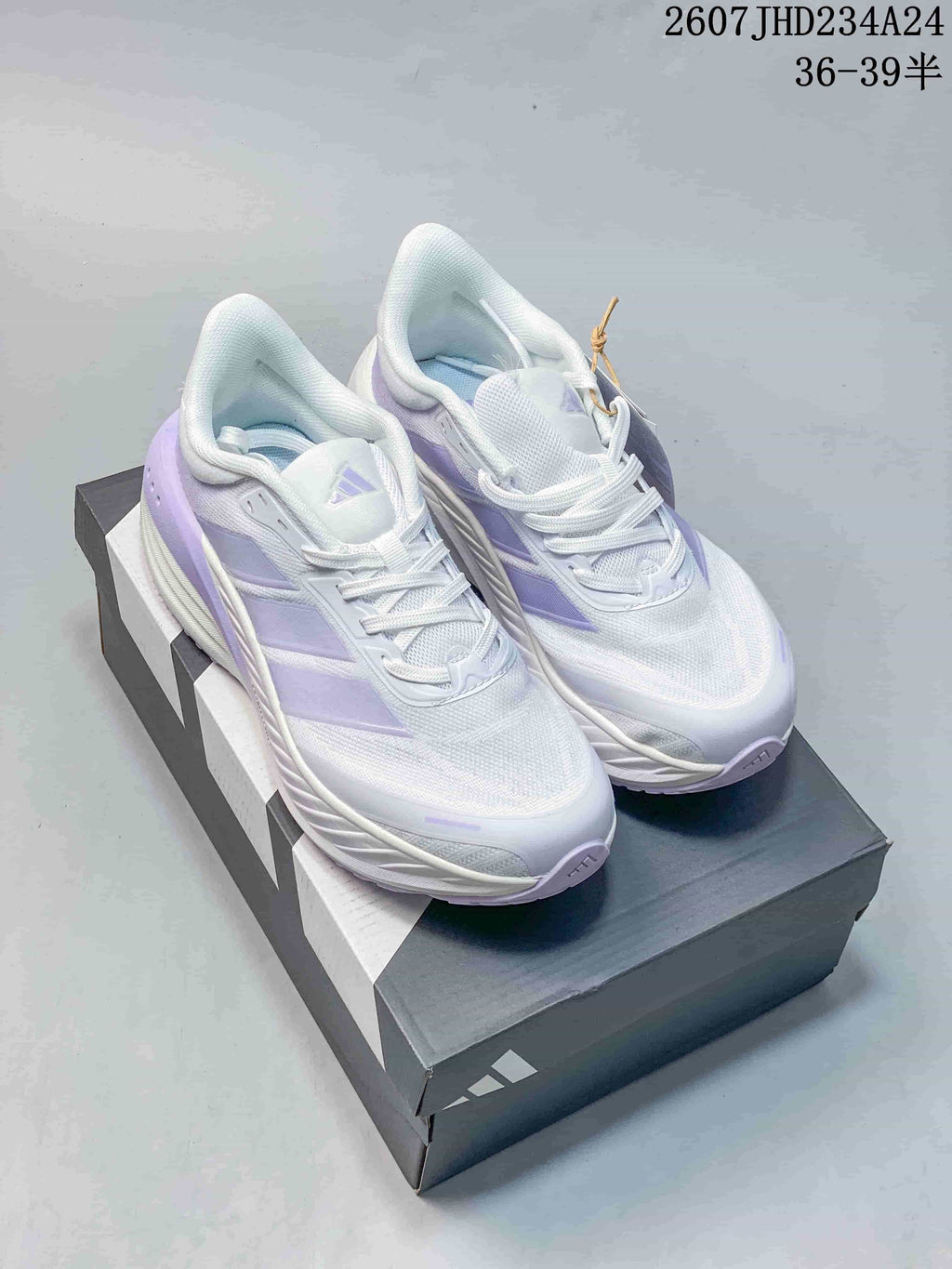 Pair of white and lavender adidas low-top sneakers displayed on an adidas shoebox.