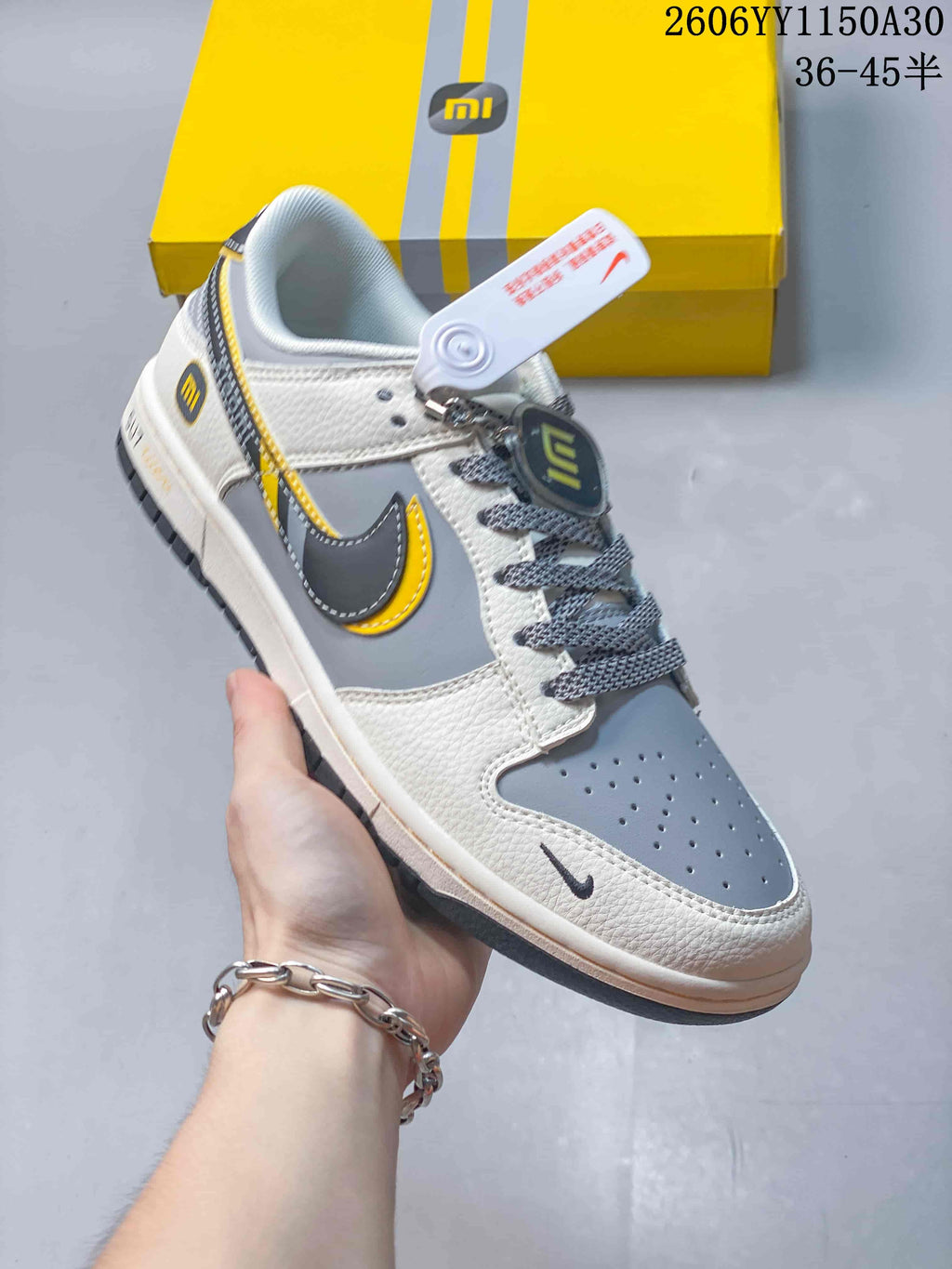 Close side view of a white and gray low-top sneaker with black and yellow details