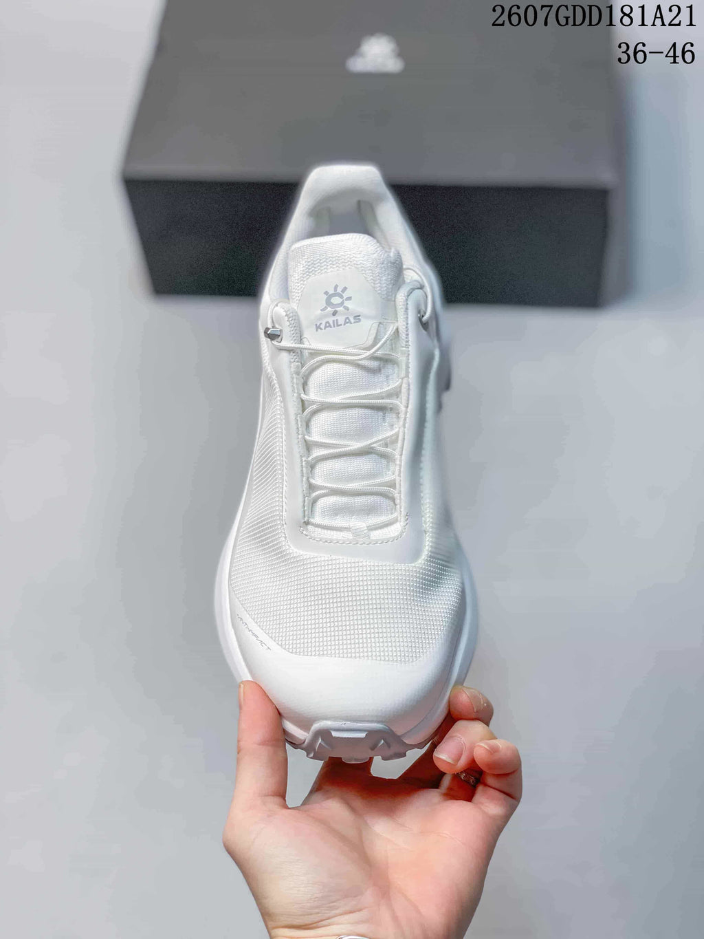 Top view of the white shoe showing the tongue logo, lace toggle system and textured forefoot.