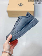 Side profile of a black low-top sneaker showing the layered upper panels and textured outsole.