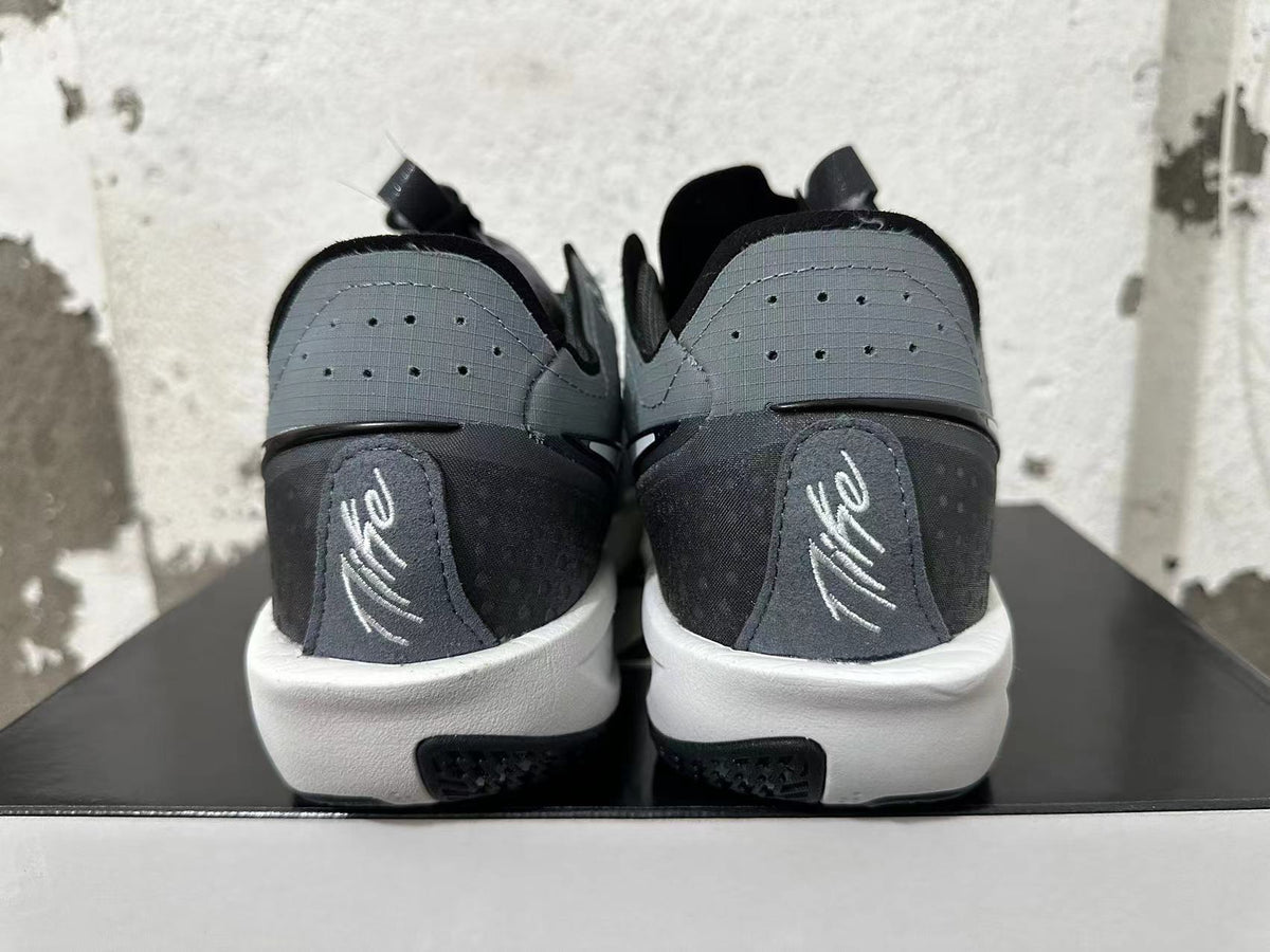 Rear view of black and grey low-top shoes with perforated heel panels and white midsoles.