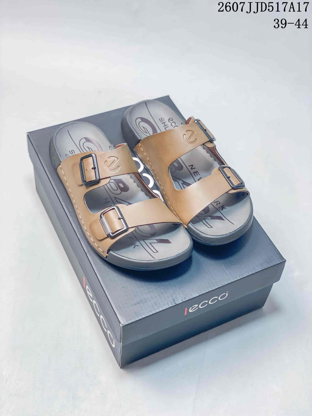 Brown and black ECCO two-buckle sandals displayed on a branded shoe box; image text shows style code 2607JJD517A17 and size range 39-44.