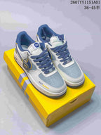 Nike Air Force 1 ’07 Low sneakers with white, blue-gray, and yellow details on a yellow box.