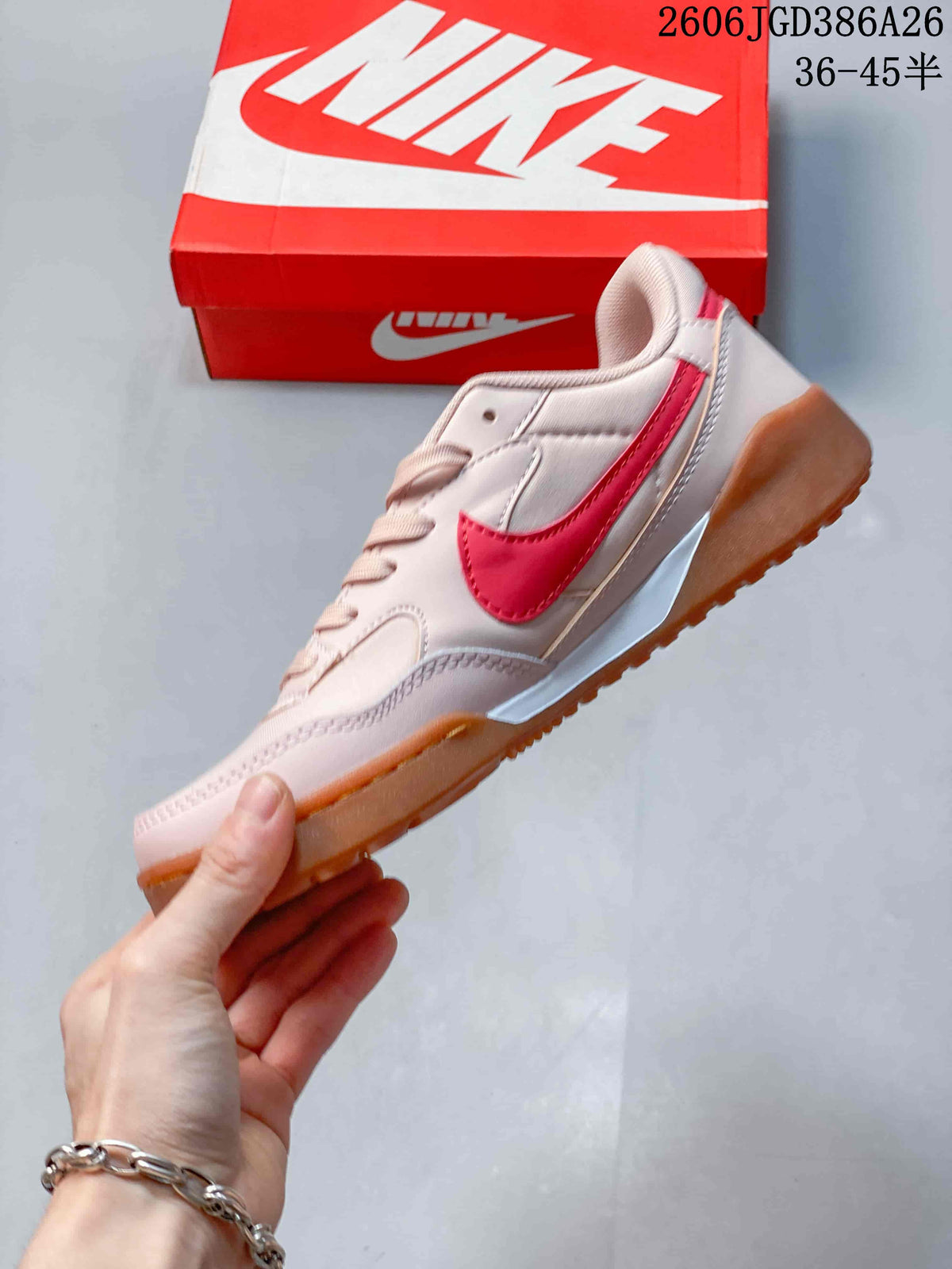 Side view of the pale pink sneaker with red Nike side branding, layered panels and a gum-colored outsole.