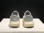 Rear view of the pair showing the gray heel panels, layered heel detail, cream-colored midsoles, and black outsole edges.