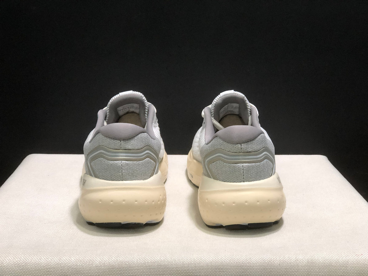 Rear view of the pair showing the gray heel panels, layered heel detail, cream-colored midsoles, and black outsole edges.
