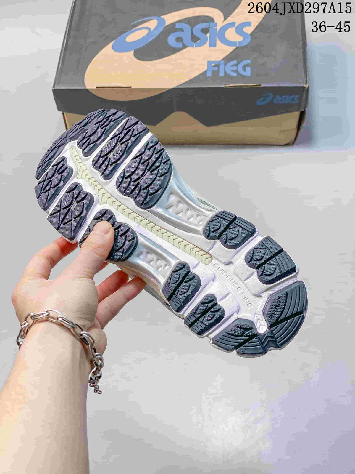 Underside of an ASICS sneaker showing a segmented dark tread outsole
