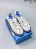 Pair of white and gray Adidas Gazelle sneakers displayed on a blue Adidas shoebox, with the Gazelle side marking visible.