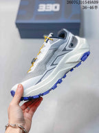 Side profile showing the grey textile-style upper, layered white midsole, heel structure, and purple outsole.