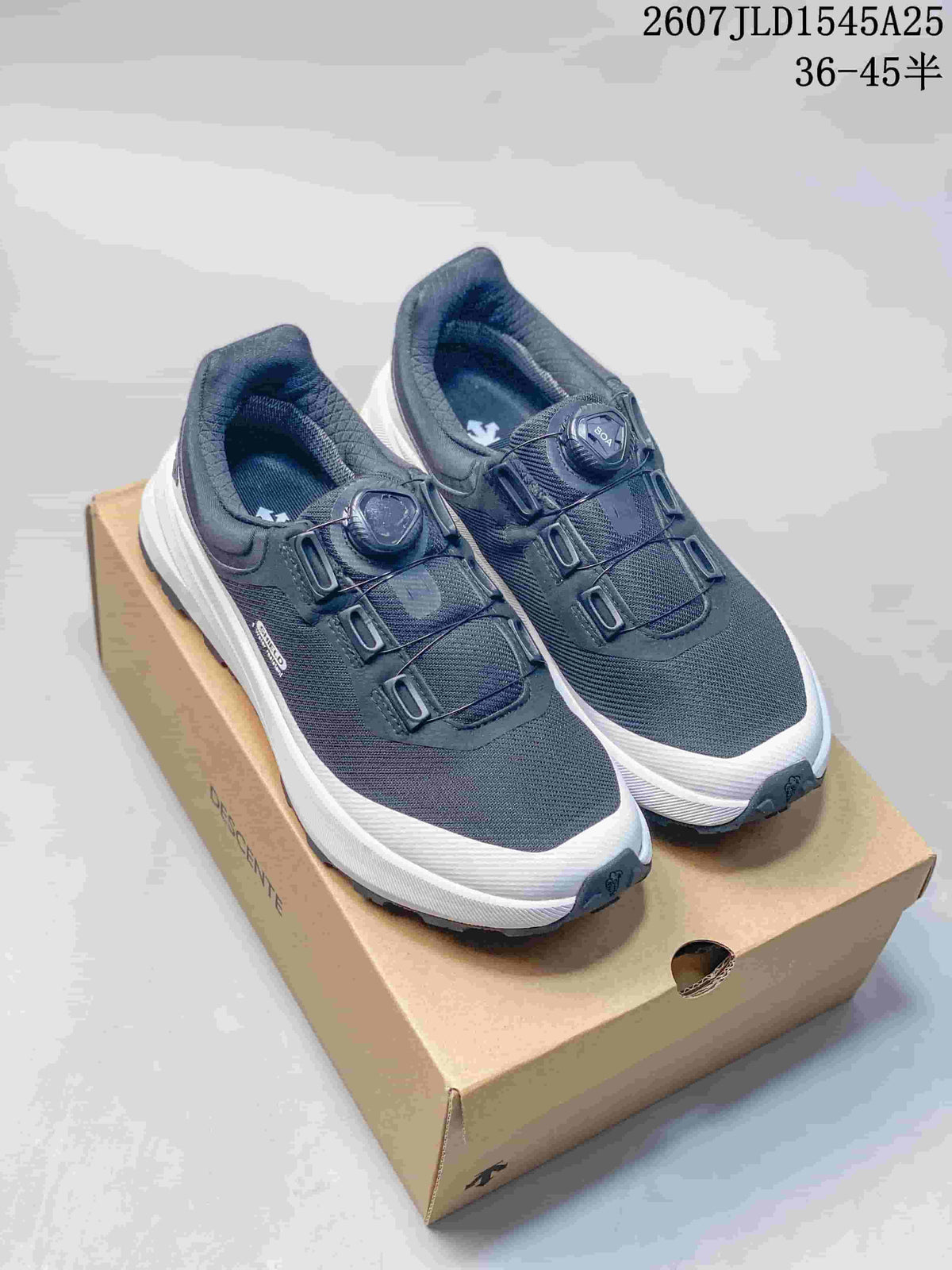 Pair of dark DESCENTE SHIELD Mantrix sneakers with white midsoles displayed on a shoebox.