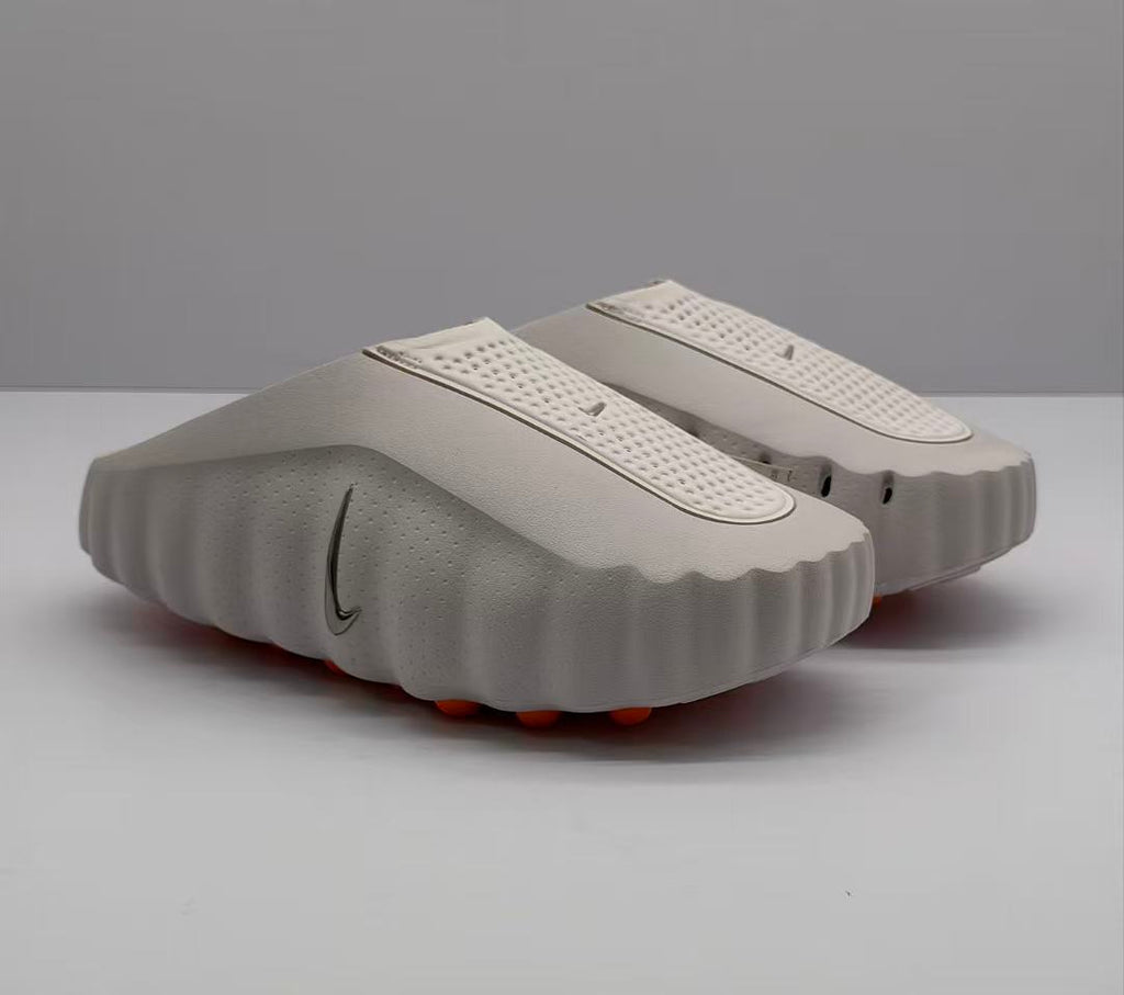 Three-quarter view of a pair of light pink and white Nike slide sandals with perforated straps and textured soles.