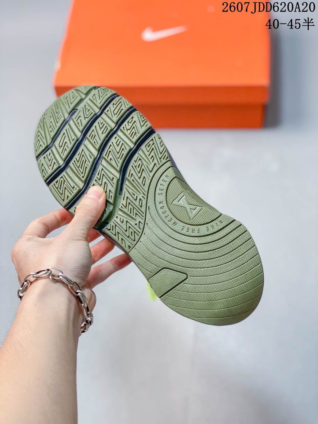 Underside view of the olive green Nike training shoe showing a segmented geometric tread pattern and circular midfoot detail.