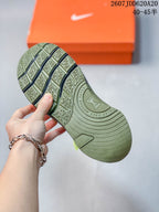 Underside view of the olive green Nike training shoe showing a segmented geometric tread pattern and circular midfoot detail.
