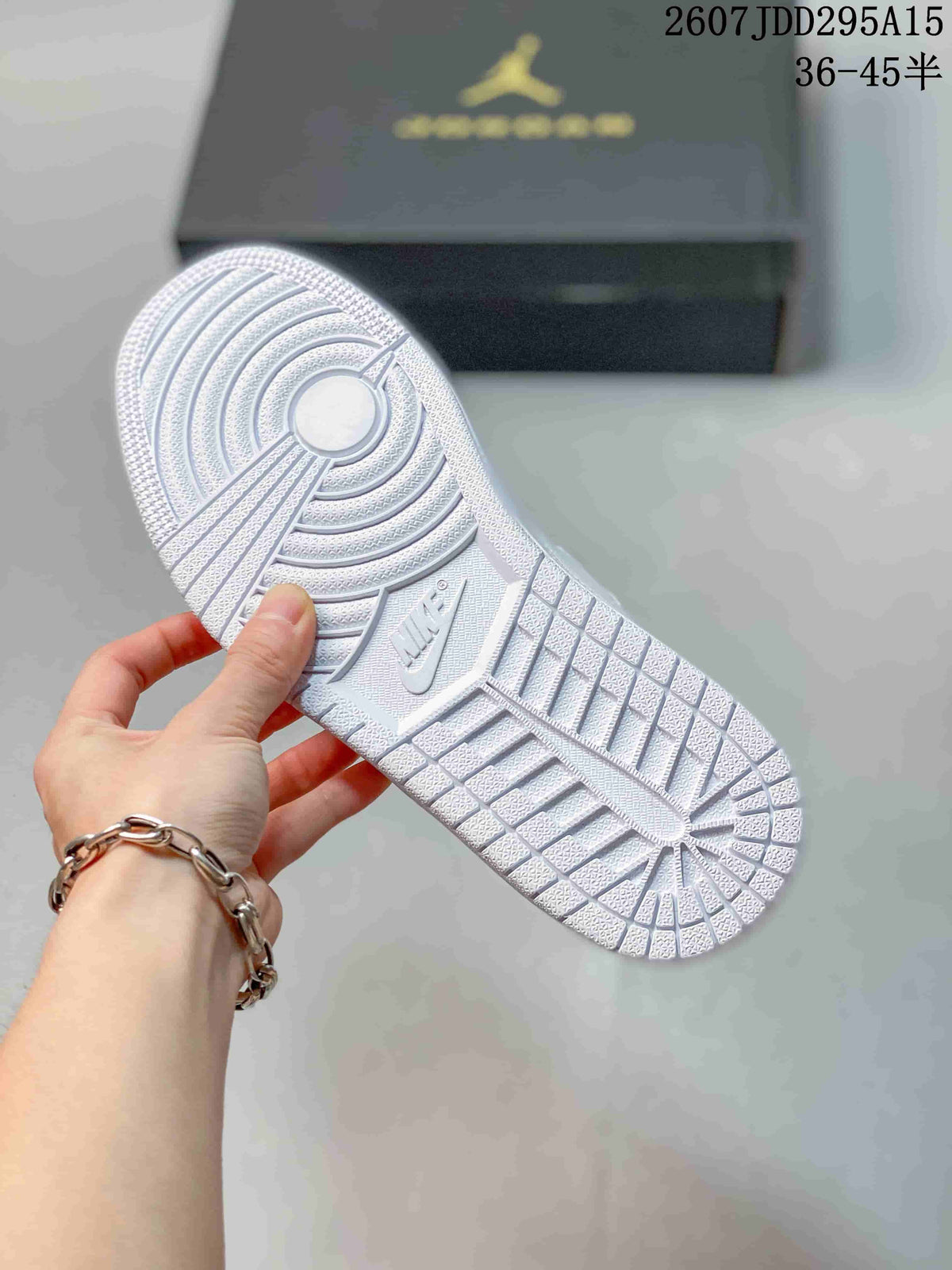 Bottom view of the white sneaker showing the textured rubber outsole and circular traction pattern.