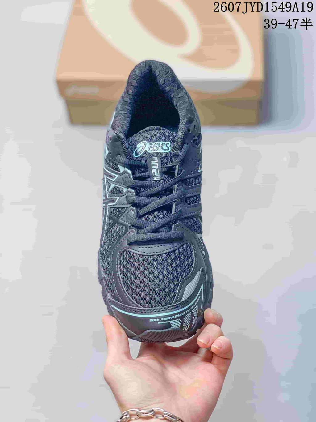 Top view of a black and gray ASICS sneaker showing the lace layout, mesh-look toe panel, branded tongue, and light aqua accent details; image text shows style code 2607JYD1549A19 and size range 39–47.5.