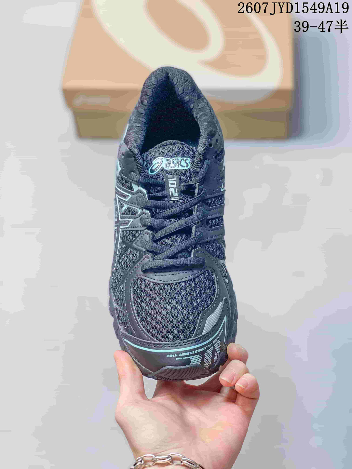 Top view of a black and gray ASICS sneaker showing the lace layout, mesh-look toe panel, branded tongue, and light aqua accent details; image text shows style code 2607JYD1549A19 and size range 39–47.5.