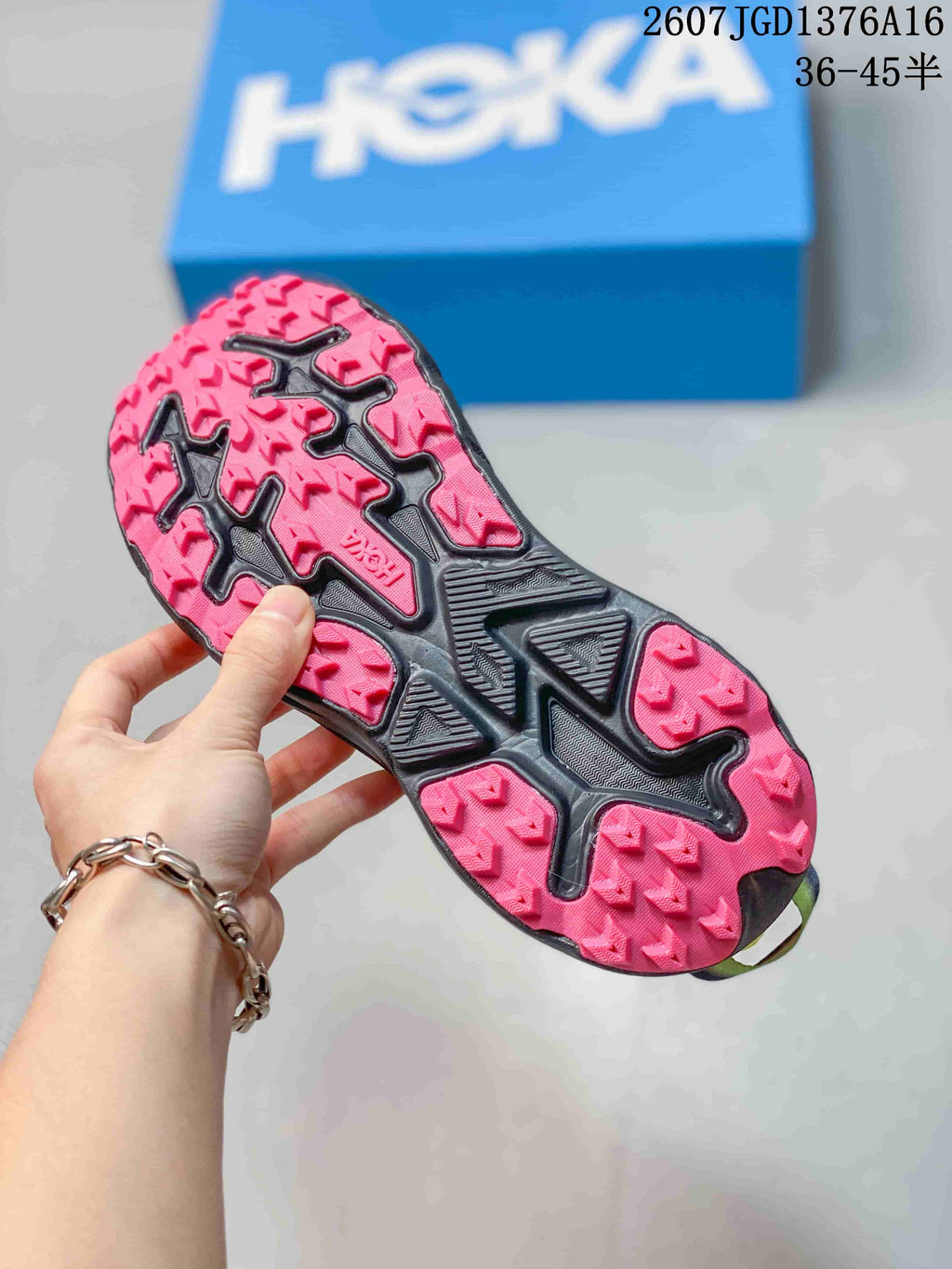 Outsole view showing the pink-and-black patterned tread on a HOKA running shoe.