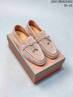 Pair of pale neutral loafers with moc-toe stitching and tassel details