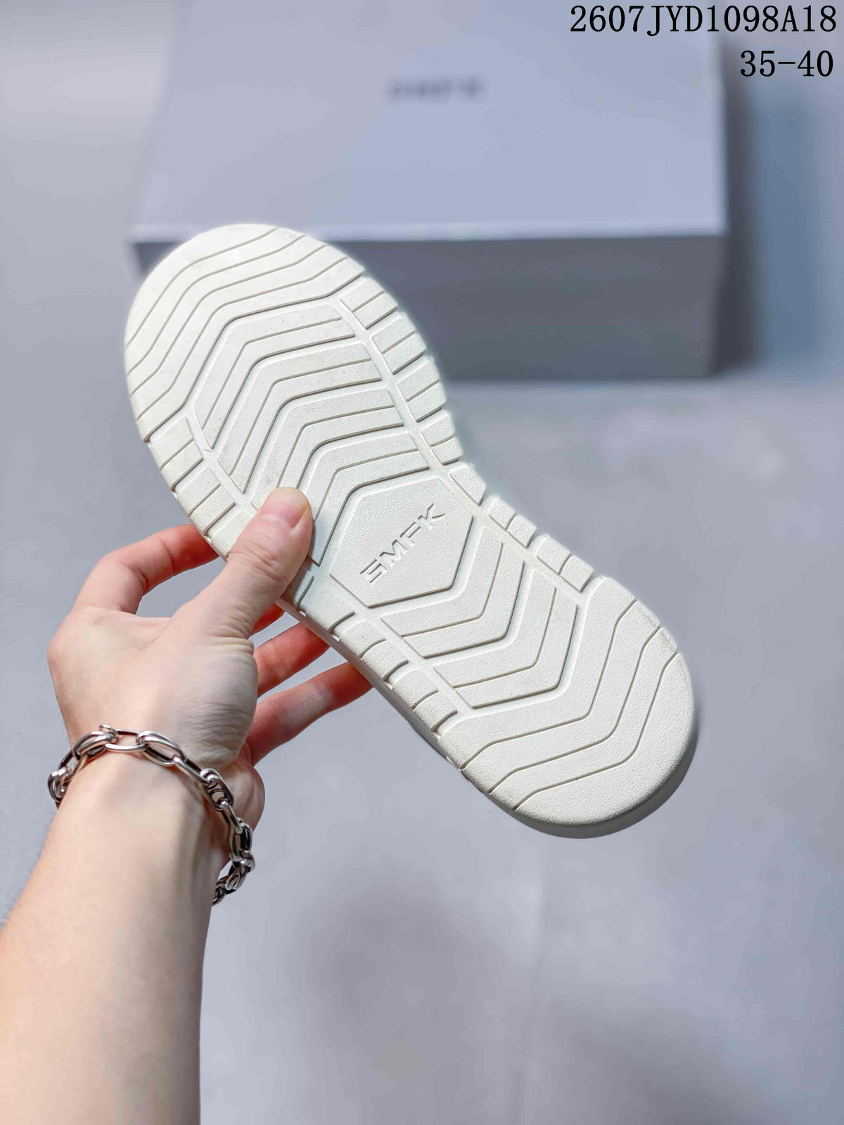 View of the textured white rubber outsole with SMFK branding