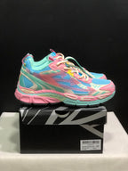 Side view of the colorful pink, mint and blue sneakers resting on a black-and-white branded shoe box.