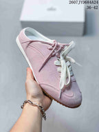 Angled side view of the pink sneaker showing the lace-up upper, stitched overlays, and outsole edge.