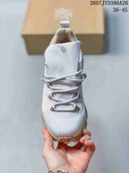 Front view of the sneaker showing the layered cord lacing, light gray upper, padded tongue, and toe branding.