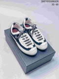 Black and white Chanel low-top sneakers displayed on a dark box, showing the rounded toe, patterned laces, and contrasting panels.