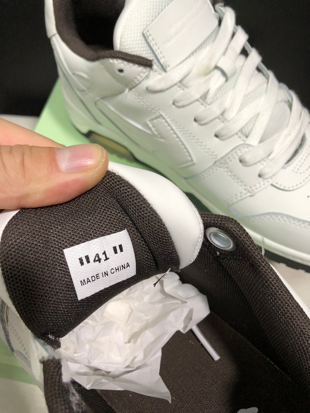Close-up of the white sneaker upper, laces, padded tongue, dark collar lining, and size label marked 41.
