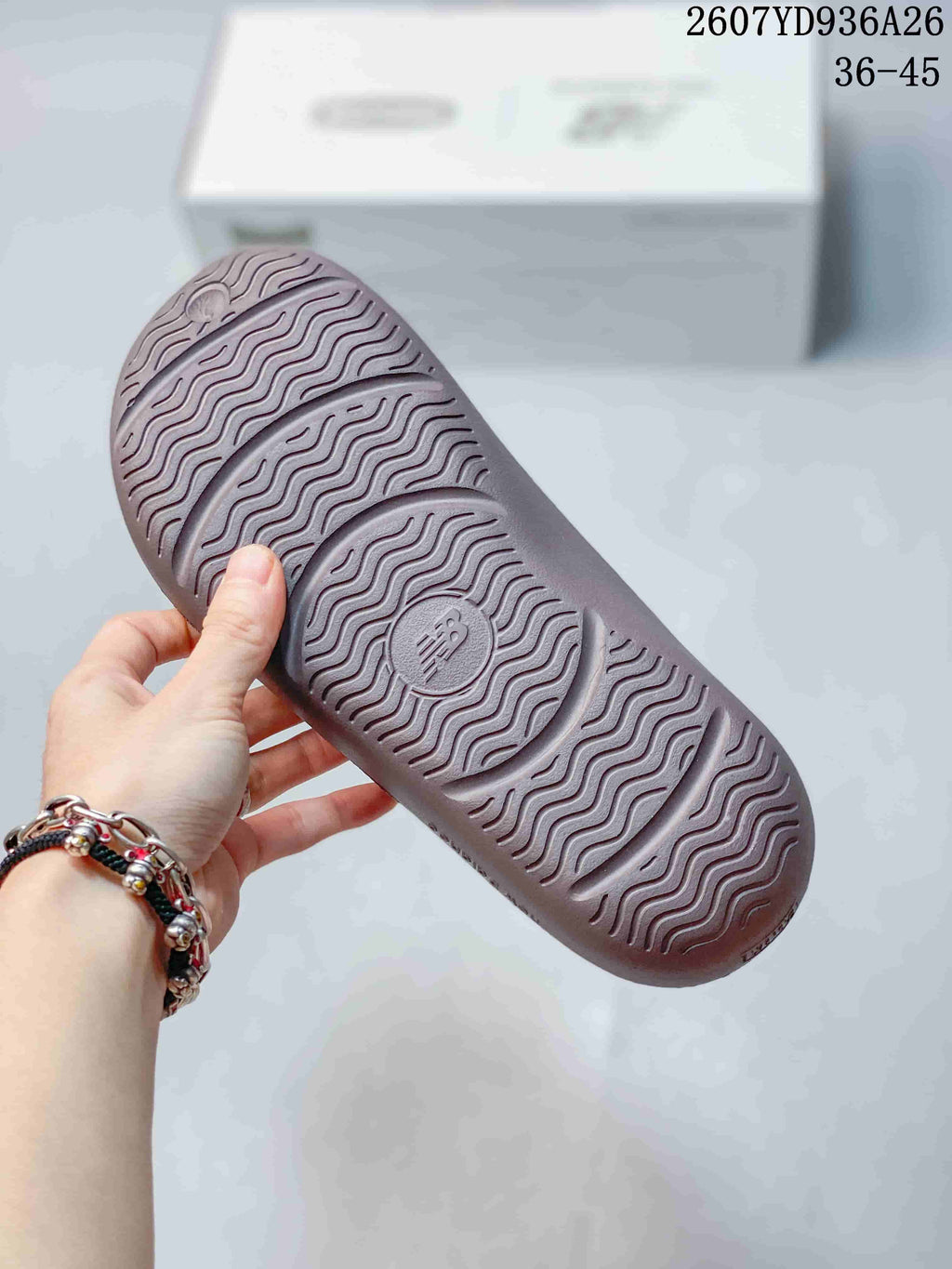 Close view of the sandal outsole showing a repeating wavy tread pattern and a central New Balance logo.