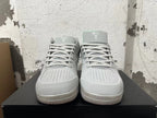 Front view of light grey low-top basketball shoes with laces, perforated toe panels, and teal tongue accents.