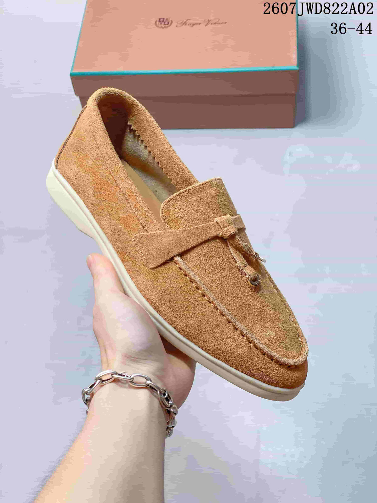 Close view of a tan loafer showing the strap and decorative tassel