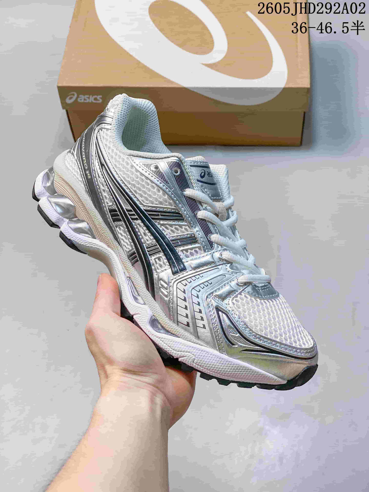 ASICS GEL-KAYANO 14 sneaker in silver and white with dark accents, shown from the side.