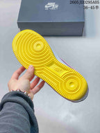 Close-up of the yellow rubber outsole with concentric circular traction grooves; a Nike Air Force 1 shoebox is visible behind it.