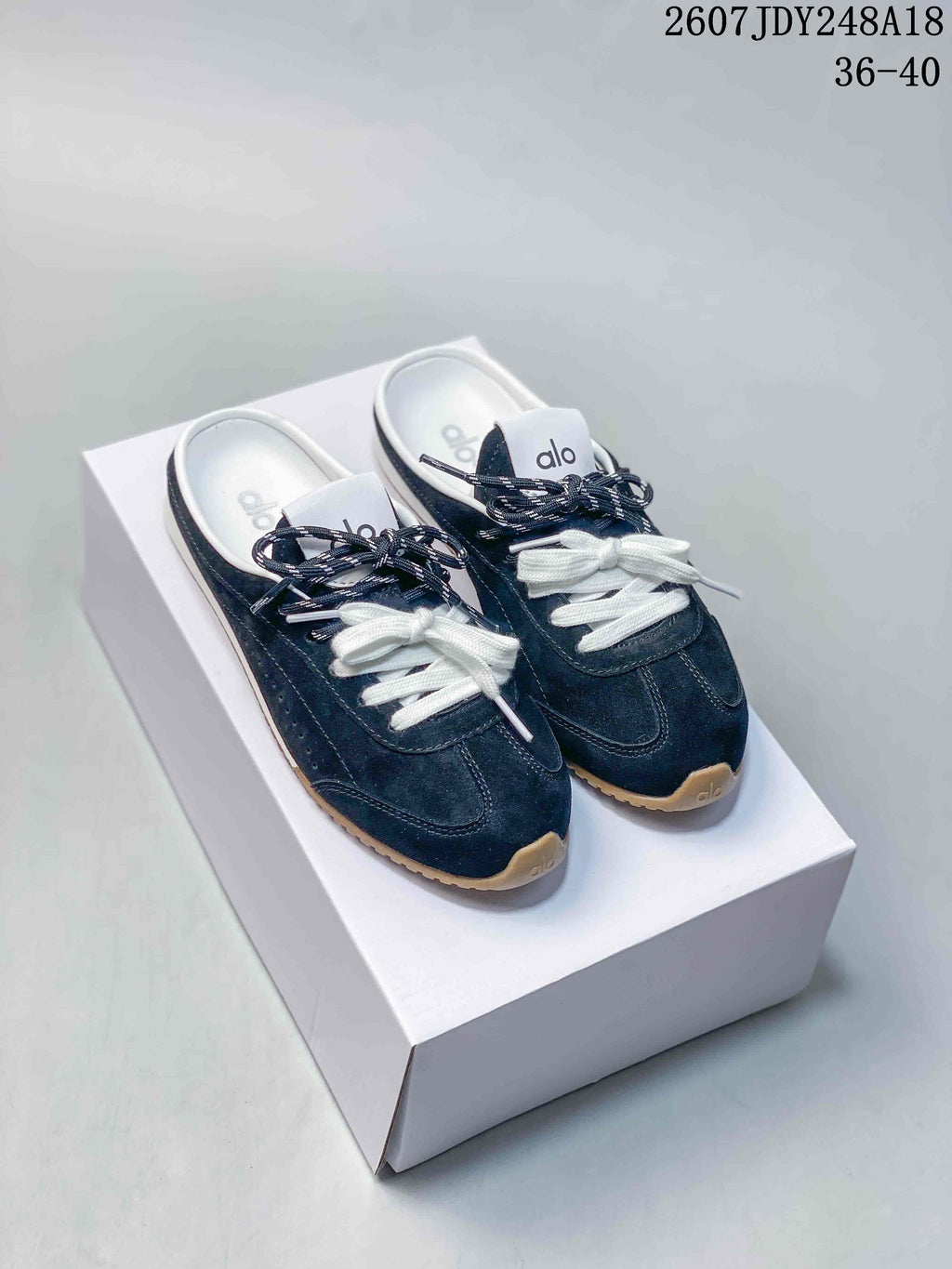Navy alo Sunset mule sneakers with white and navy laces displayed on a white shoebox.
