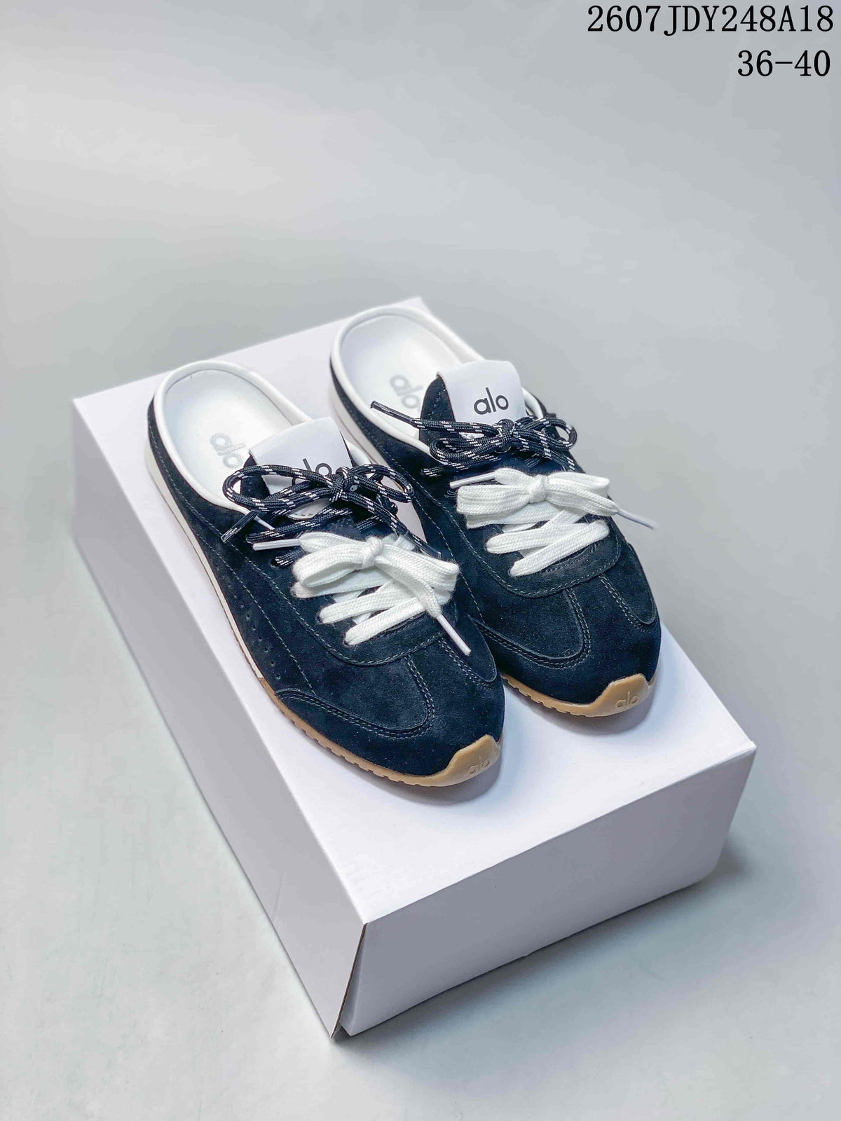 Navy alo Sunset mule sneakers with white and navy laces displayed on a white shoebox.