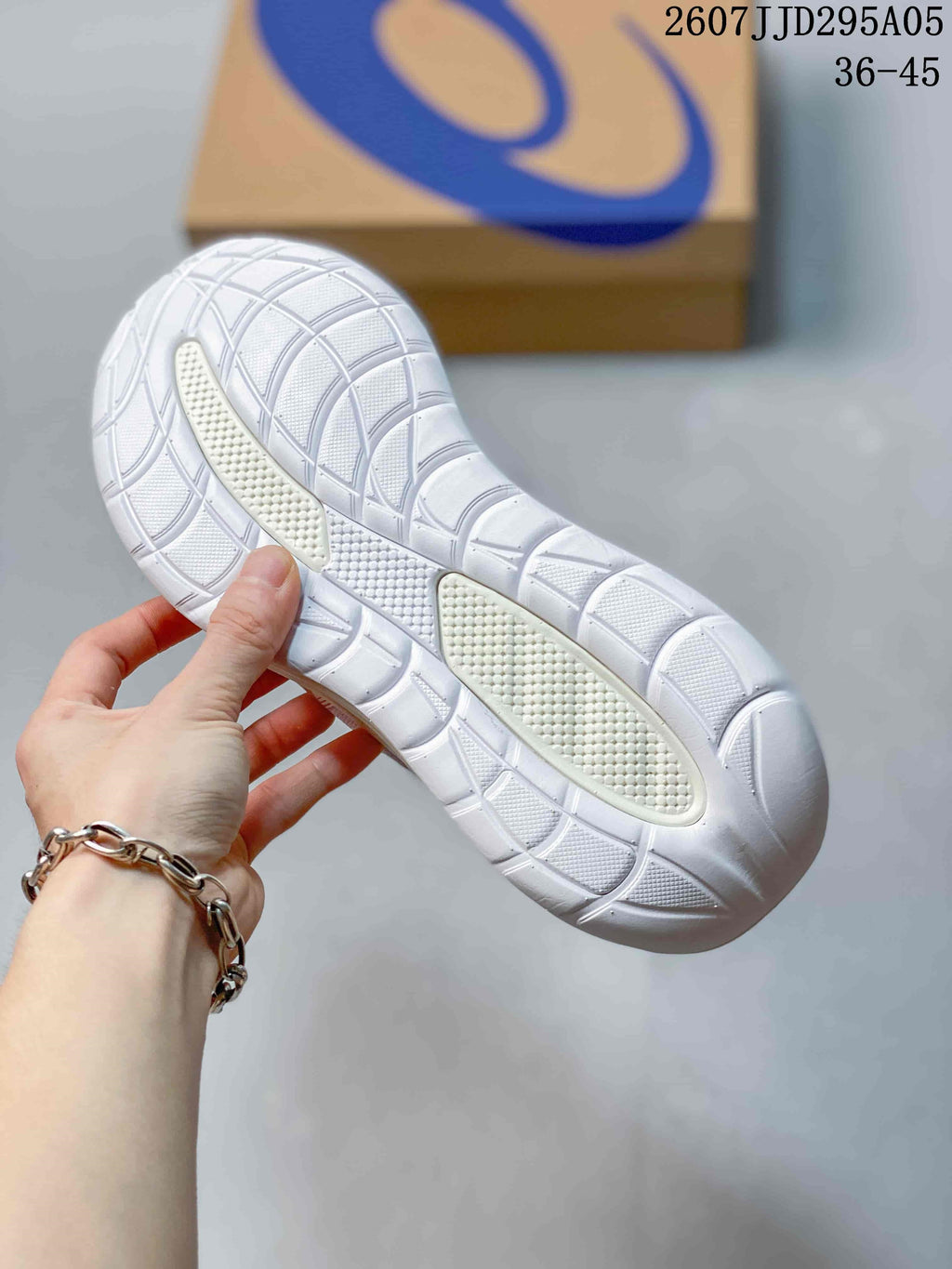 Close view of the white rubber outsole with segmented traction grooves on a pink and white ASICS sneaker.