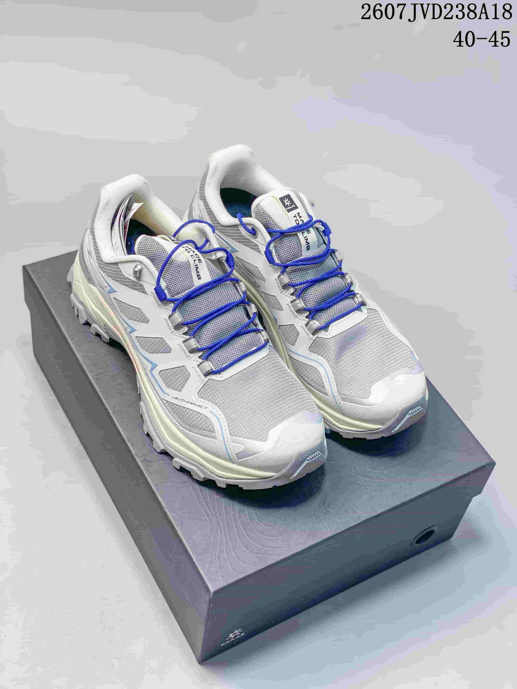 White KAILAS hiking shoes with bright blue laces and light blue accents displayed on a shoebox.