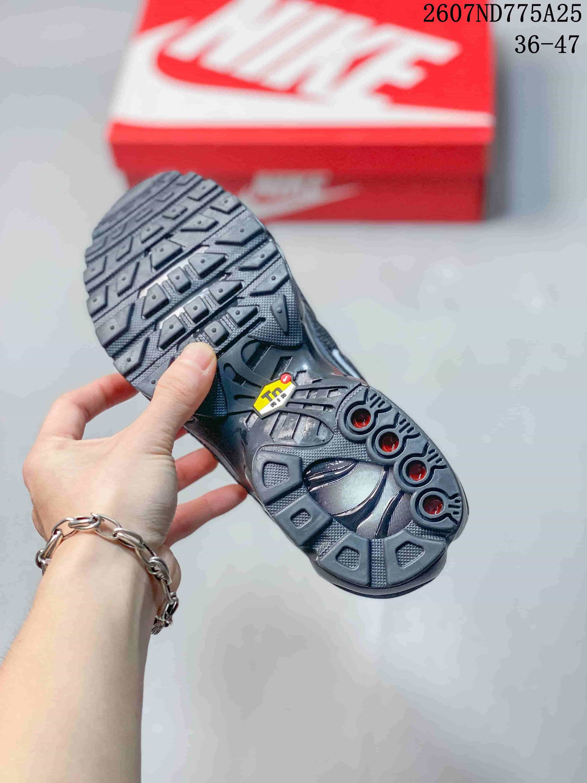 Underside view of a black sneaker showing the sculpted outsole with geometric tread and circular details.