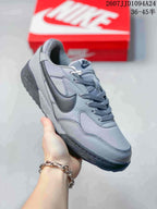 Angled side view of the gray sneaker showing the layered upper, dark Swoosh, laces, and outsole.