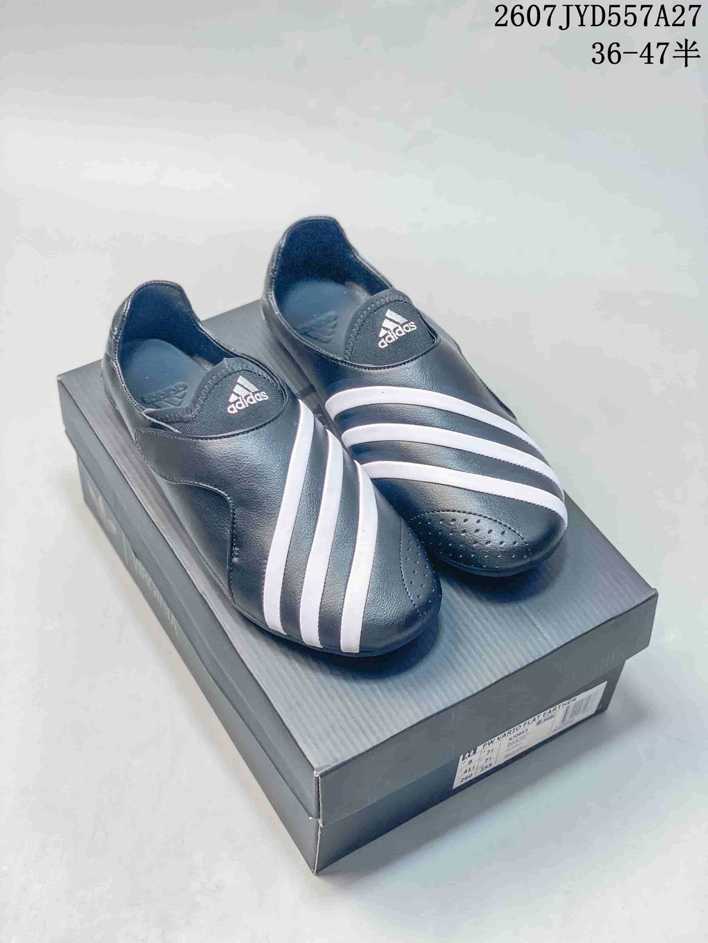 Pair of black and white adidas slip-on sneakers displayed on a shoebox