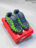 Pair of black and vivid green Nike Shox TL sneakers on a red shoebox